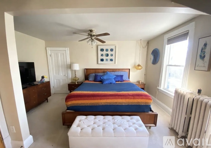A bedroom with a bed, a ceiling fan, and a window.
