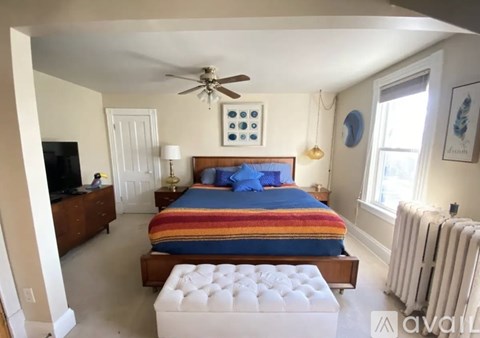 A bedroom with a bed, a ceiling fan, and a window.