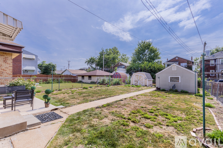 A backyard with a concrete walkway and a metal grate.