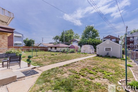 A backyard with a concrete walkway and a metal grate.