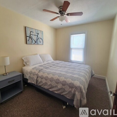 A bedroom with a bed, nightstand, and a painting of a bicycle on the wall.