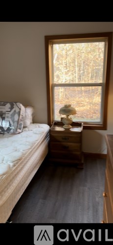 A bedroom with a bed, nightstand and window.