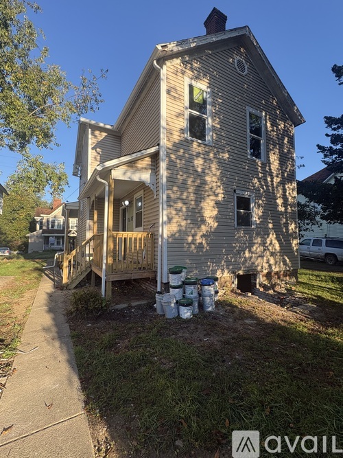 A house with a porch and a tree in front of it.