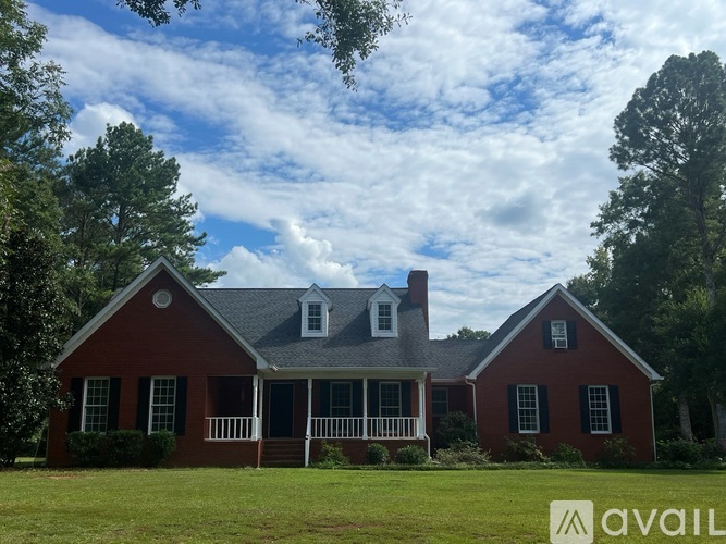 A red house with a white porch and a sign that says "AVAIL".