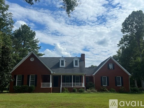 A red house with a white porch and a sign that says "AVAIL".