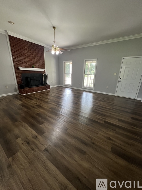 A room with wooden flooring and a brick wall fireplace.