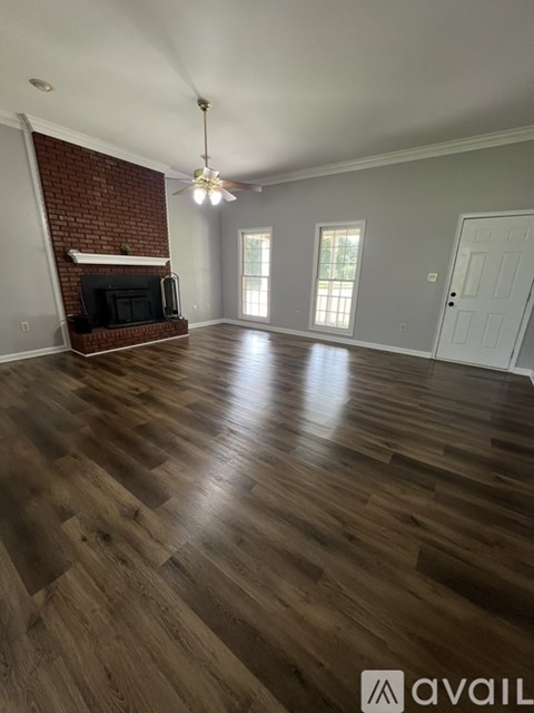 A room with wooden flooring and a brick wall fireplace.
