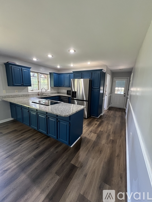 A kitchen with dark blue cabinets and a wooden floor.