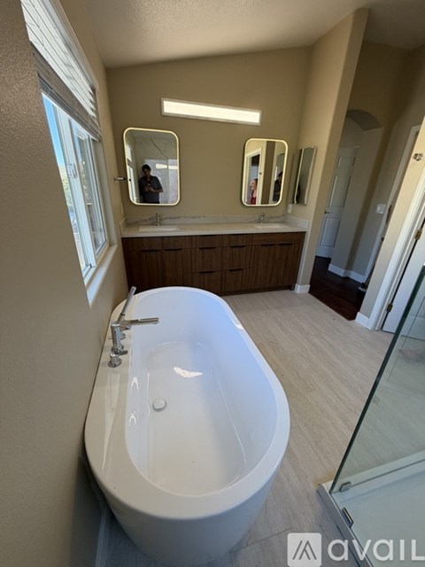 A white bathtub with a silver faucet is in a bathroom with a large mirror above it.