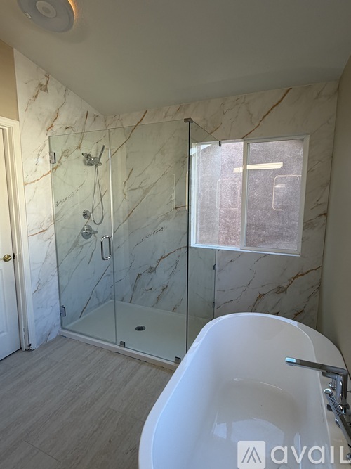 A bathroom with marble walls and a white bathtub.
