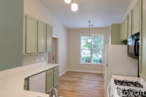 A kitchen with green cabinets and a white dishwasher.