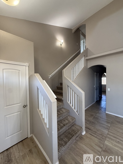 A staircase with a white railing and a light on the wall.