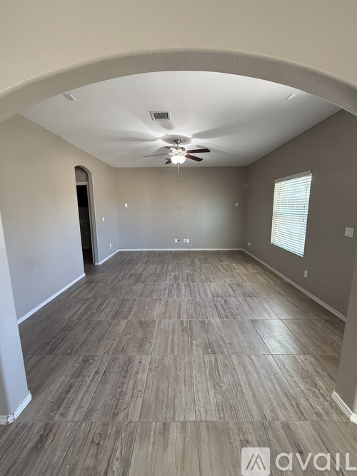 A spacious room with a ceiling fan and lighting fixture.
