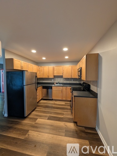 A kitchen with wooden cabinets and a black refrigerator.