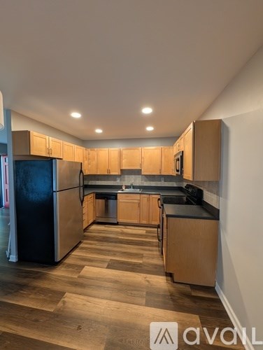 A kitchen with wooden cabinets and a black refrigerator.