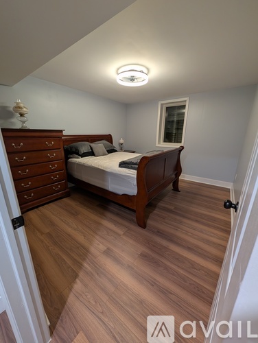 A bedroom with a bed, dresser, and wooden floors.