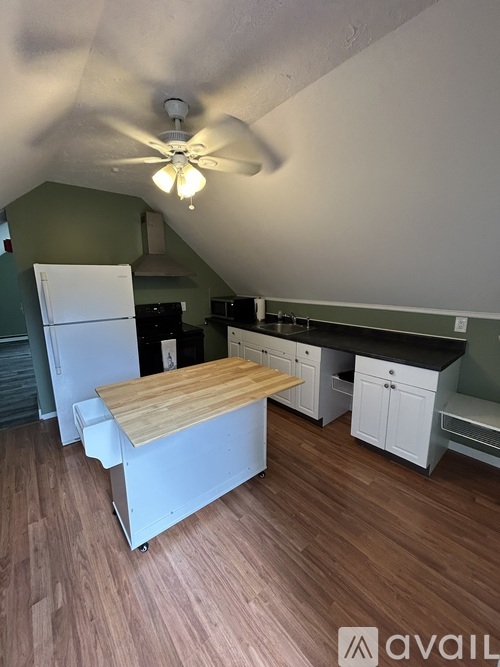 A kitchen with a white refrigerator, wooden countertop, and a ceiling fan.