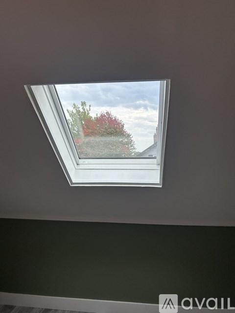A skylight in a room with a view of a house and trees.