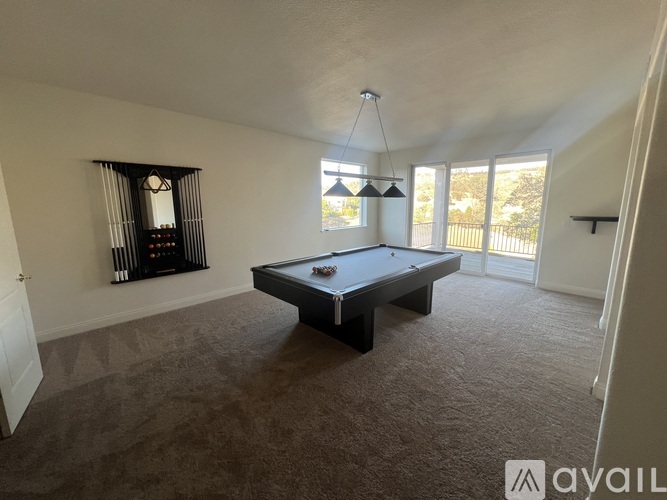 A room with a pool table and a window with curtains.