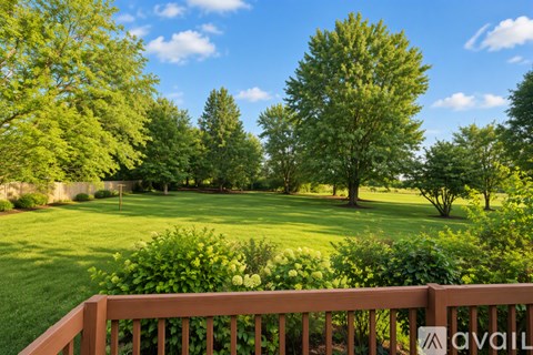 A wooden fence with a sign that says "AVAIL" in front of a lush green lawn and trees.