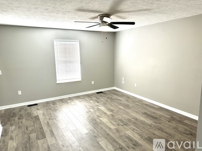 A room with a ceiling fan and wooden flooring.