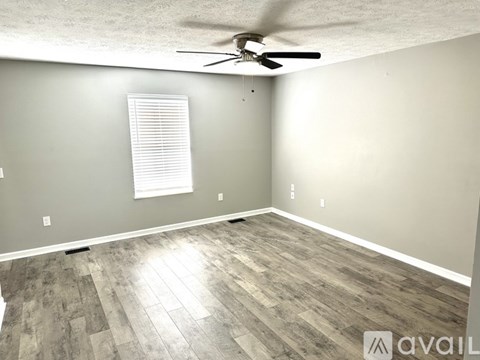 A room with a ceiling fan and wooden flooring.
