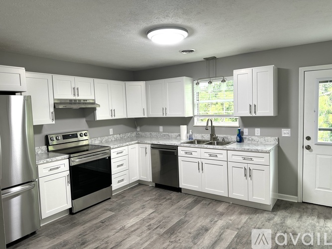 A kitchen with white cabinets and stainless steel appliances is available for rent.