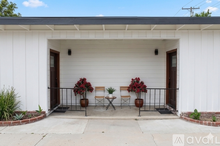 A white house with a black metal railing and a small table and two chairs on the porch.