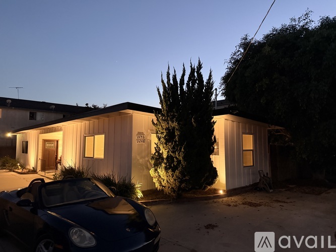 A house with a car parked in front of it at night.