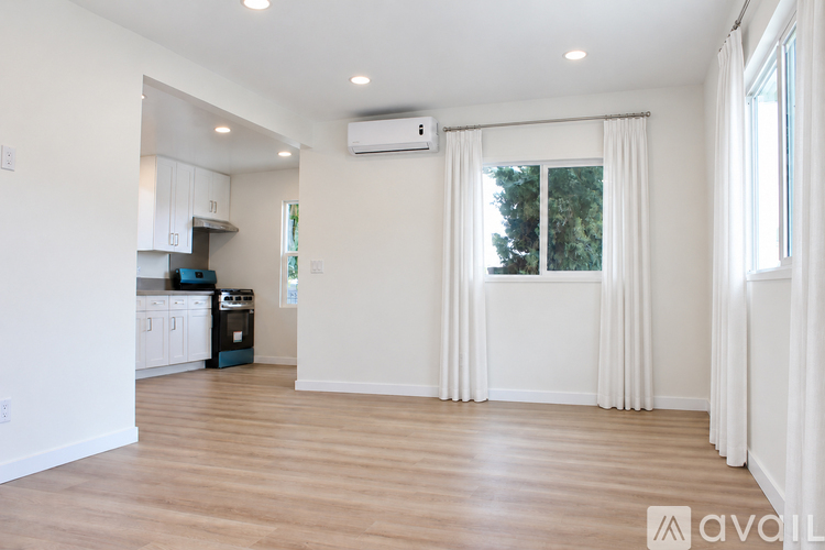 A spacious living room with a kitchen area in the background.