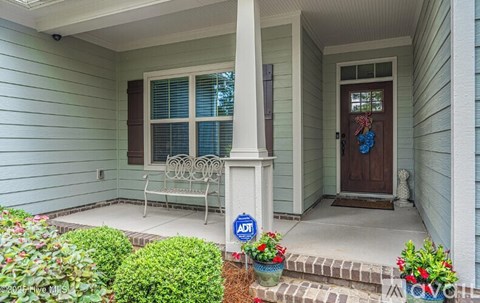 A front porch with a chair and a sign that says "ADT".
