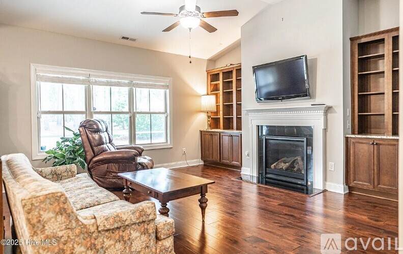 A living room with a fireplace and a television on the wall.