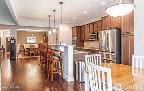 A kitchen with wooden floors and a dining table with chairs.