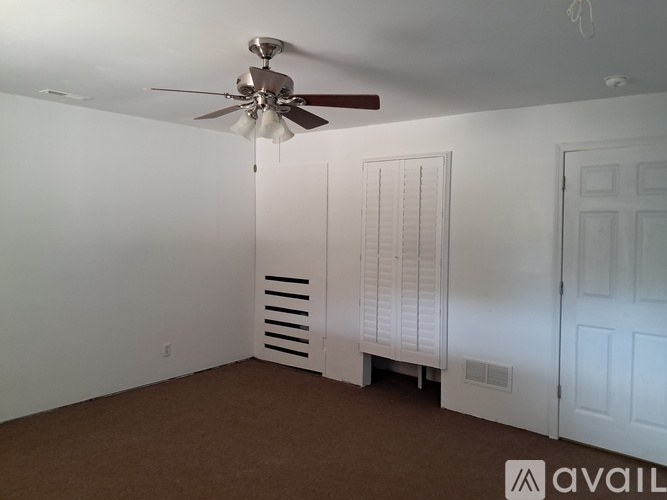 A room with a ceiling fan and two doors.