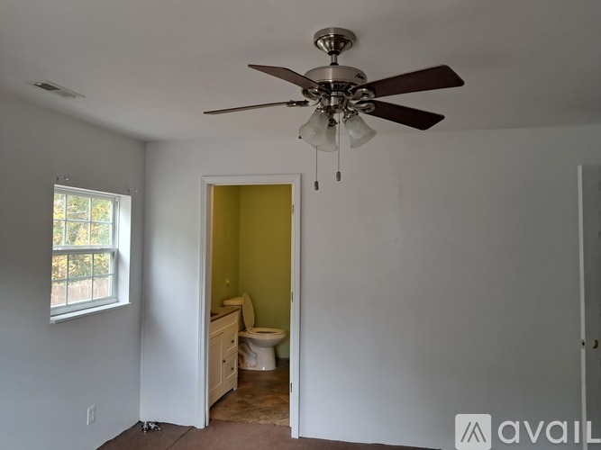 A room with a ceiling fan and a toilet in the corner.