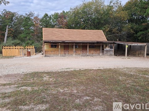 A wooden building with a brown roof is surrounded by a wooden fence.