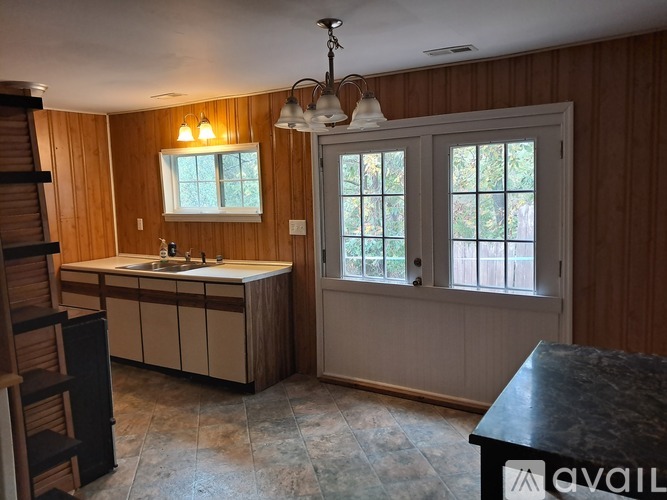 A kitchen with wooden walls and a black countertop.