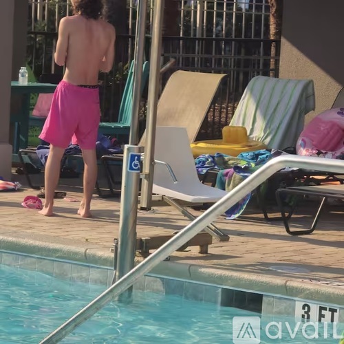 A man in pink shorts stands by a pool.