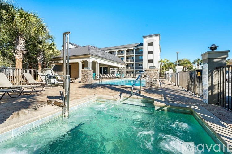 A pool area with a hot tub and lounge chairs in front of a building.