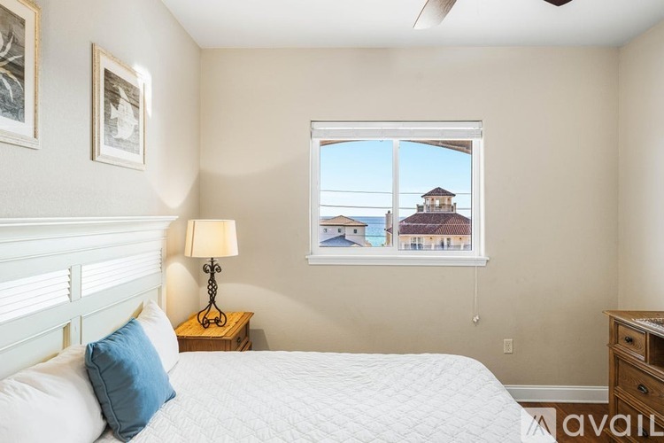 A bedroom with a bed, a lamp, and a window overlooking a building.