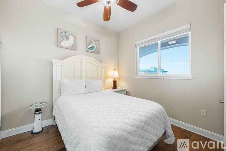 A bedroom with a white bed and a ceiling fan.