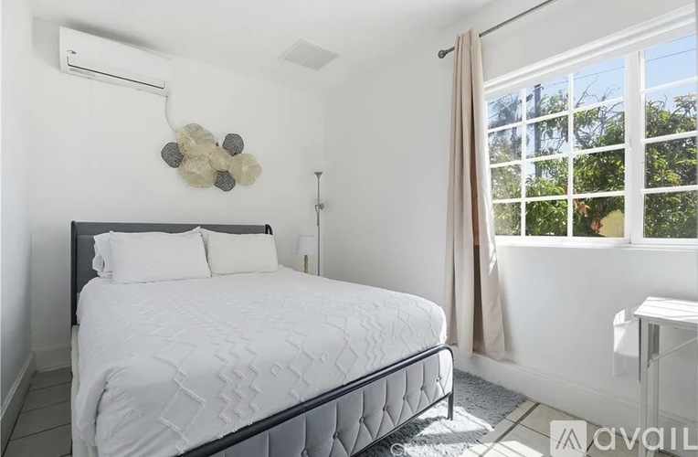 A bedroom with a large bed and a window with curtains.