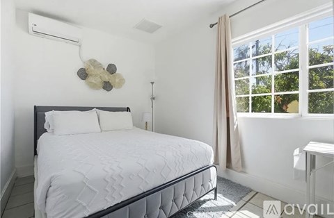 A bedroom with a large bed and a window with curtains.
