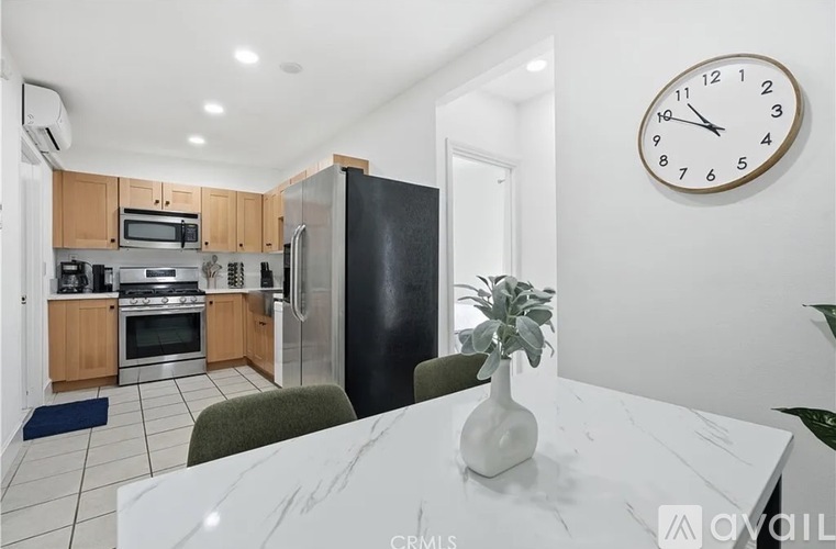 A kitchen with a white table and a clock on the wall.