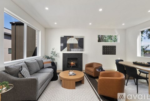 A living room with a grey couch, a fireplace, and a dining table.