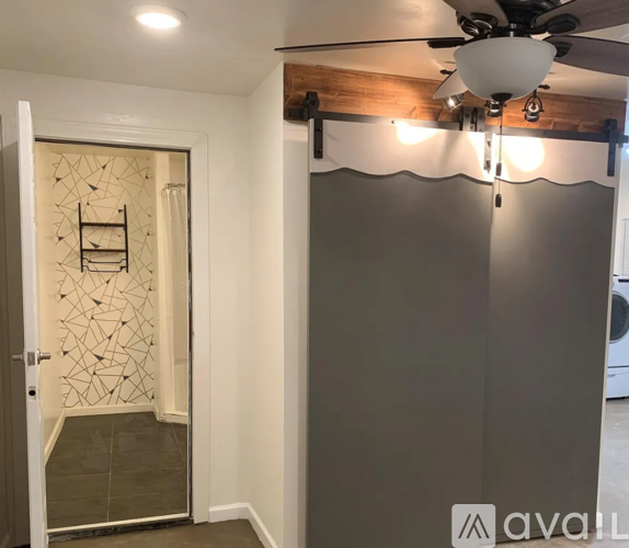 A room with a ceiling fan and a wall with a geometric pattern.