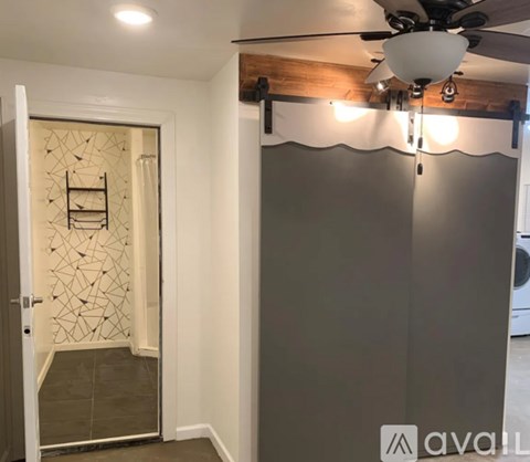 A room with a ceiling fan and a wall with a geometric pattern.
