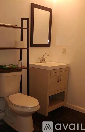 A bathroom with a toilet, sink, and mirror.