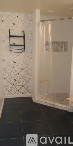 A bathroom with a black tiled floor and a white shower curtain.