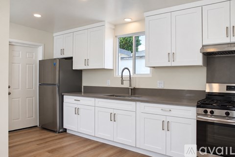 A kitchen with white cabinets and a stainless steel refrigerator.